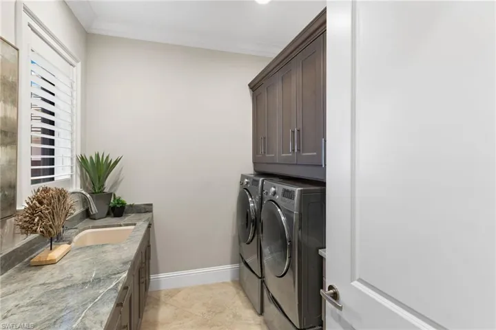 Laundry room with crown molding, cabinet space, washer and dryer, and light tile patterned flooring