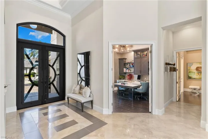 Foyer entrance with a high ceiling, crown molding, and french doors
