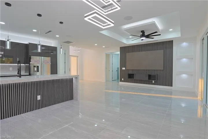 Unfurnished living room with a ceiling fan, recessed lighting, a fireplace, and a tray ceiling