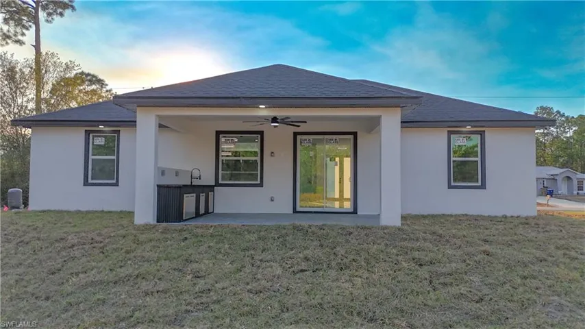 Back of property featuring ceiling fan, a patio area, a yard, and stucco siding