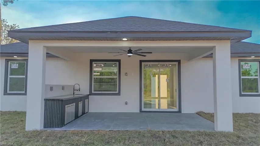 Rear view of property with a ceiling fan, roof with shingles, and stucco siding