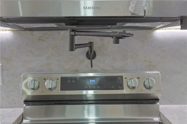 Kitchen view of light countertops, stainless steel electric range oven, and pot filler