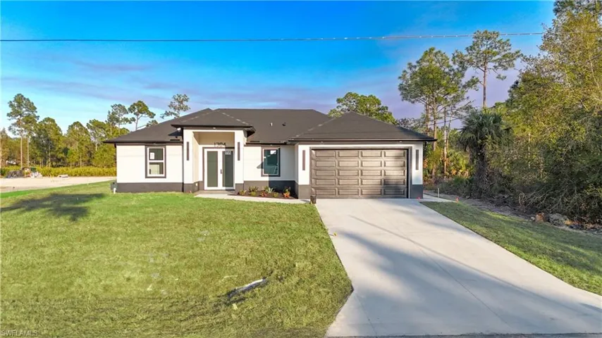 View of front of house featuring driveway, a yard, stucco siding, and an attached garage