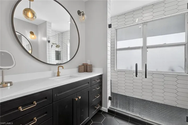 Full bathroom featuring a stall shower, vanity, and dark tile patterned flooring