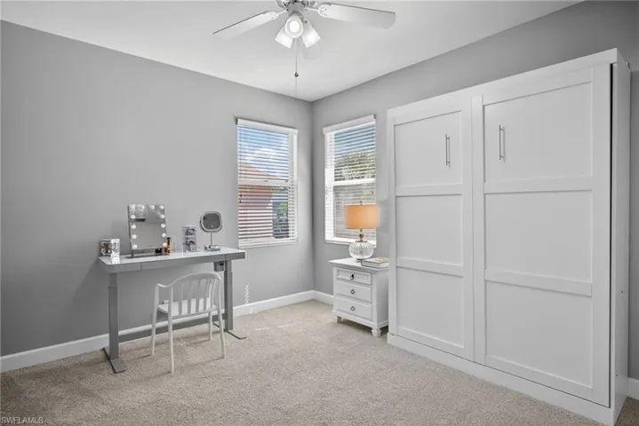 Office space featuring light carpet and a ceiling fan
