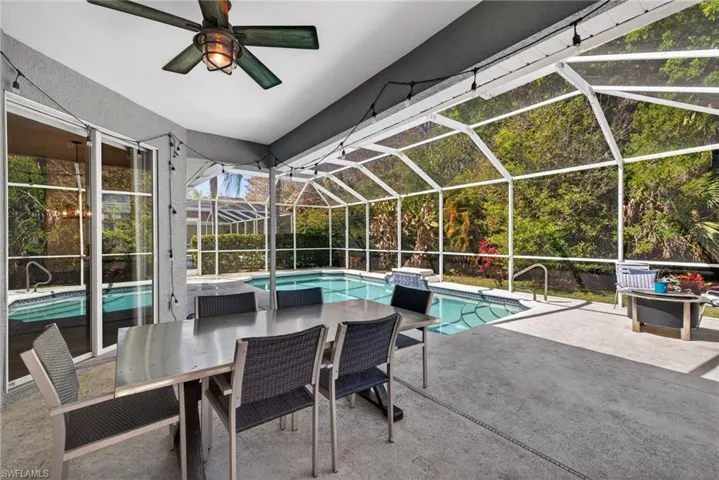 Swimming pool featuring a sunroom, a patio area, glass enclosure, and outdoor dining area