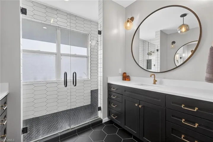 Bathroom featuring vanity, a shower stall, and dark tile patterned floors