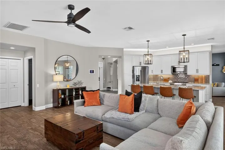Living area featuring hanging lights, dark wood-type flooring, and ceiling fan
