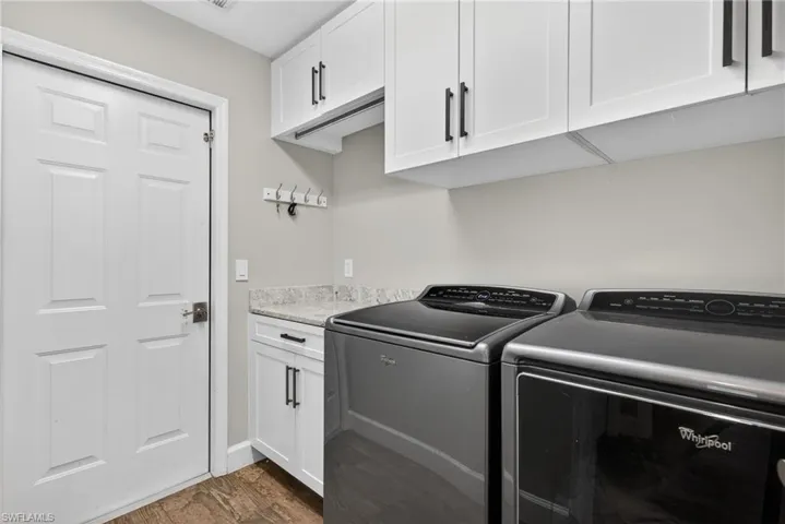 Laundry room featuring cabinet space, washing machine and clothes dryer, and dark wood-style floors