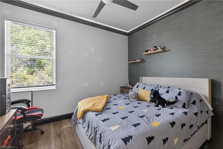 Bedroom with crown molding, wood finished floors, and ceiling fan