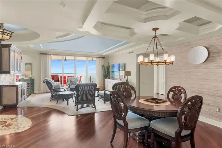 Dining space featuring coffered ceiling, suspended lighting, ornamental molding, hardwood / wood-style floors, and an accent wall