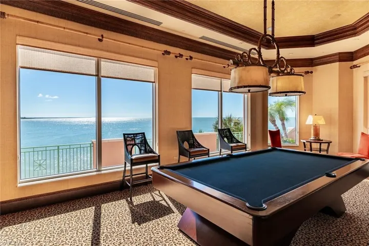 Rec room featuring a water view, ornamental molding, pool table, and a tray ceiling