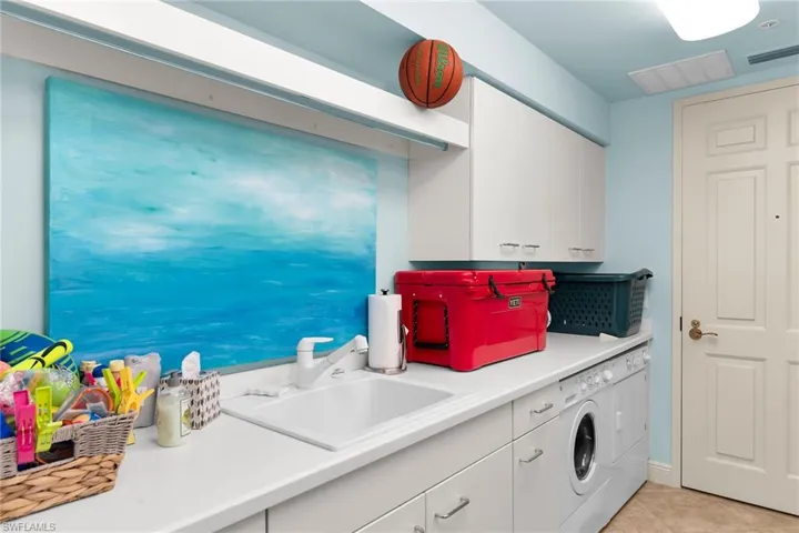 Laundry room featuring cabinet space and light tile patterned flooring