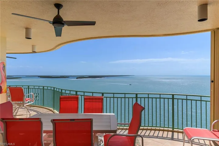 Balcony with ceiling fan, outdoor dining space, and a water view