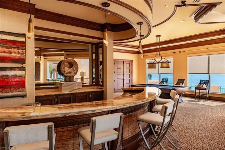 Community bar area featuring ornamental molding, healthy amount of natural light, and pendant lighting