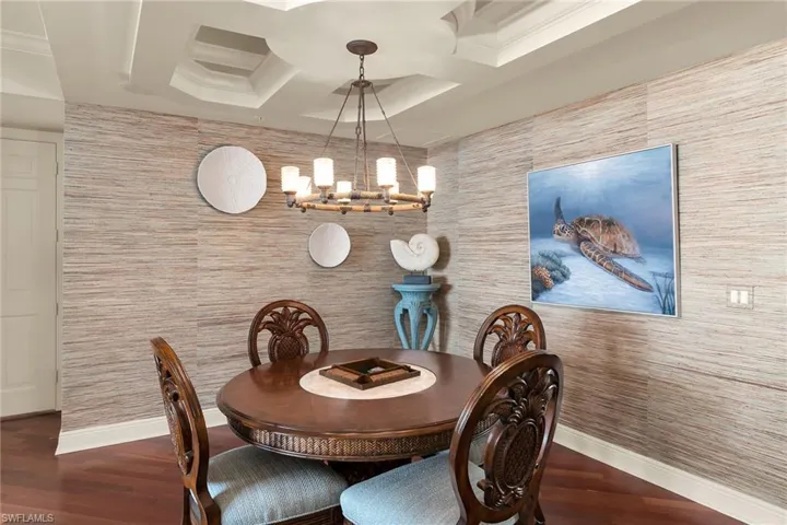 Dining area with wood finished floors, hanging lights, and a tray ceiling