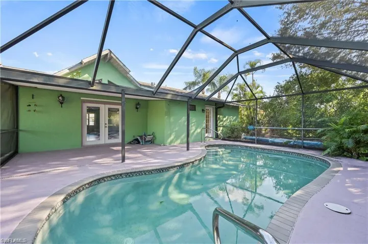 View of swimming pool featuring a patio, french doors, and glass enclosure