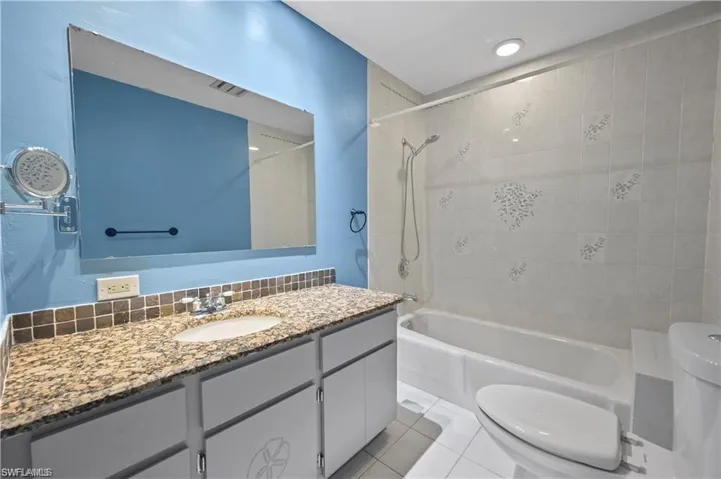 Full bathroom with toilet, tile patterned floors, vanity, backsplash, and tiled shower / bath combo