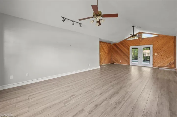 Unfurnished living room with lofted ceiling, french doors, light hardwood / wood-style flooring, and ceiling fan