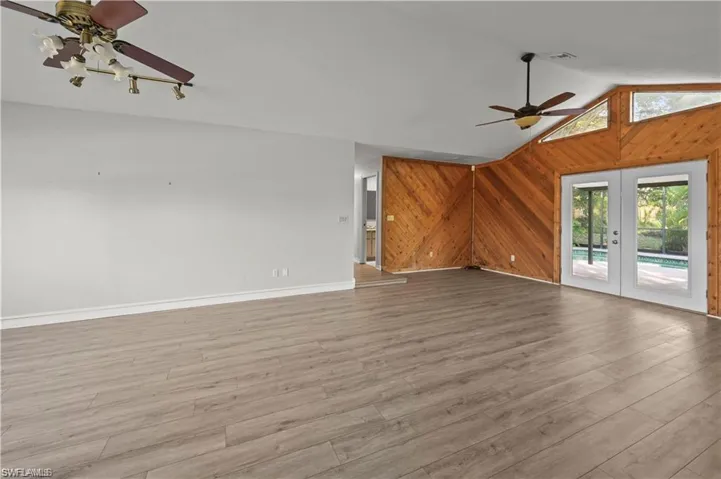 Unfurnished living room featuring ceiling fan, light hardwood / wood-style flooring, french doors, and lofted ceiling
