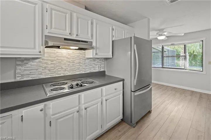 Kitchen with ceiling fan, white cabinetry, gas cooktop, and light hardwood / wood-style floors