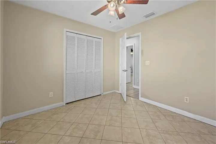 Unfurnished bedroom with ceiling fan, a closet, and light tile patterned floors