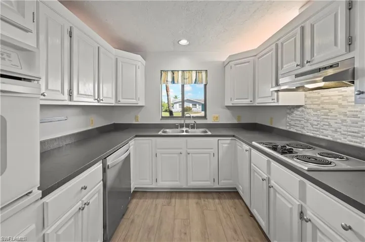 Kitchen featuring sink, white cabinetry, stainless steel dishwasher, and light hardwood / wood-style floors
