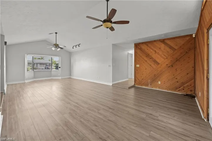 Unfurnished living room featuring ceiling fan, hardwood / wood-style floors, and vaulted ceiling