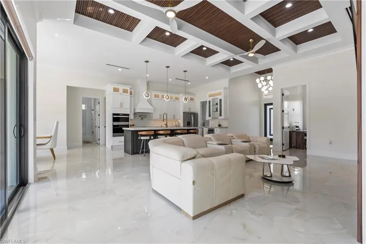 Living room with marble finish floor, a towering ceiling, coffered ceiling, and a chandelier