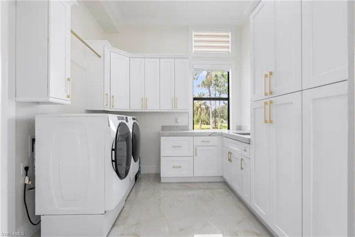 Laundry area featuring marble finish floor, independent washer and dryer, and cabinet space