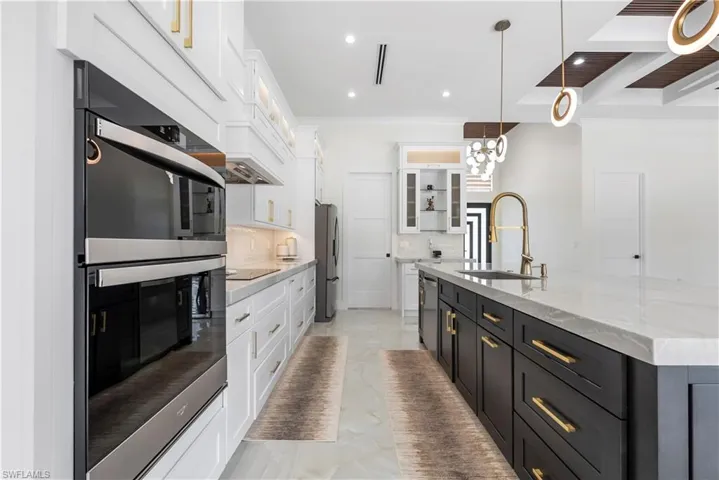 Kitchen featuring marble finish floor, white cabinets, a sink, and appliances with stainless steel finishes