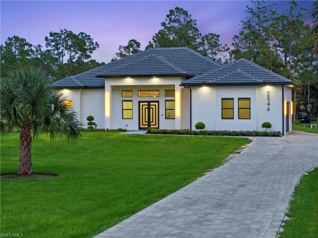 View of front facade featuring stucco siding, french doors, a tiled roof, decorative driveway, and a front yard