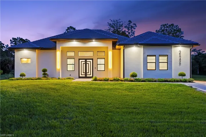 Prairie-style home featuring a front yard, a tiled roof, and stucco siding