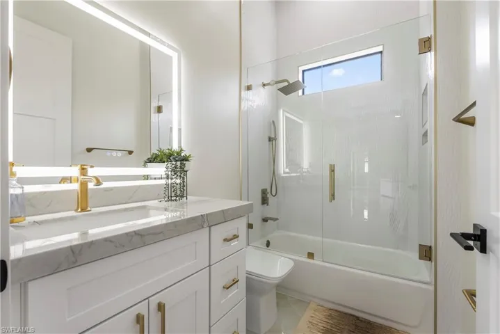 Full bath featuring combined bath / shower with glass door, toilet, and vanity