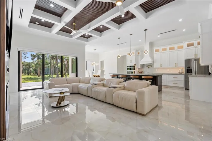 Living area with marble finish floor, ceiling fan, a towering ceiling, and coffered ceiling