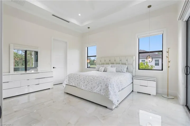 Bedroom with marble finish floor, a tray ceiling, baseboards, and visible vents