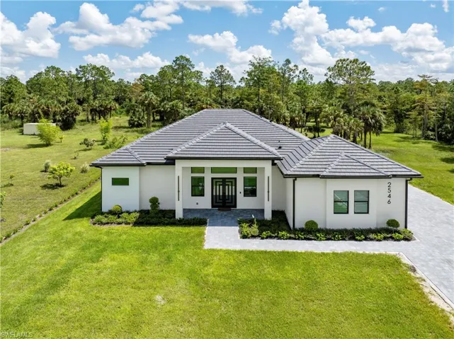 View of front facade featuring a tile roof, french doors, and a front yard