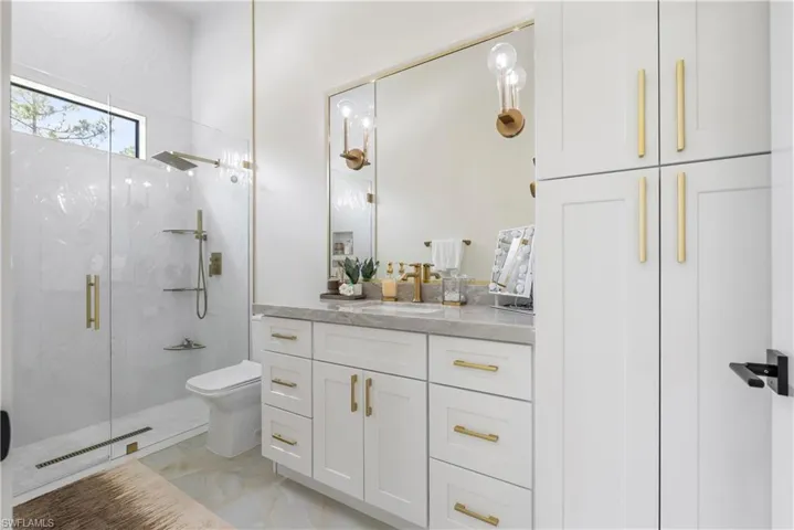 Bathroom with visible vents, marble finish floor, a marble finish shower, toilet, and vanity