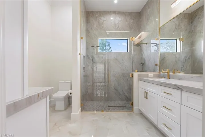 Full bath featuring marble finish floor, toilet, vanity, and a marble finish shower
