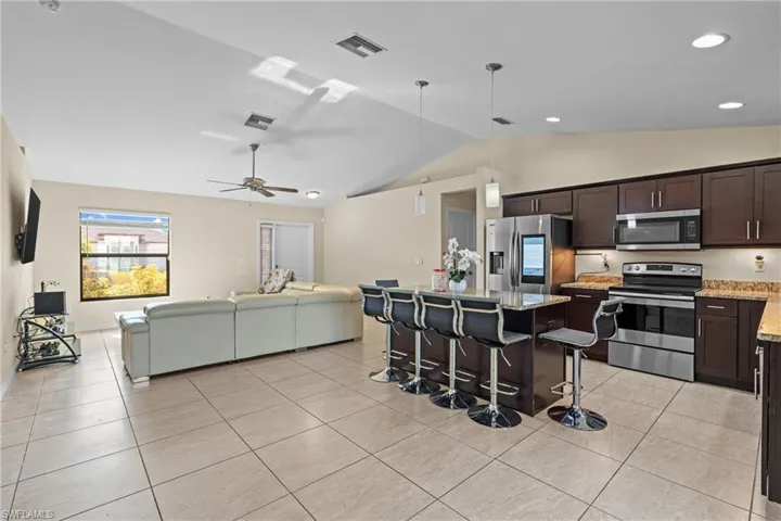 Kitchen featuring open floor plan, stainless steel appliances, dark brown cabinets, a breakfast bar, and a center island