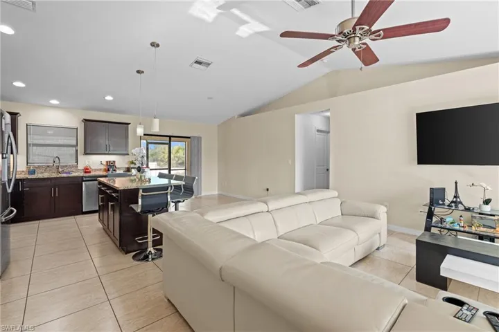 Living area with light tile patterned floors, lofted ceiling, ceiling fan, and recessed lighting