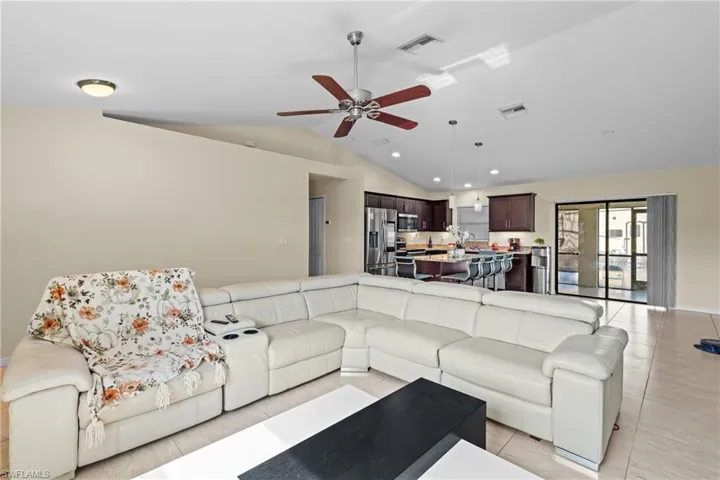 Living area with light tile patterned floors, ceiling fan, high vaulted ceiling, and recessed lighting