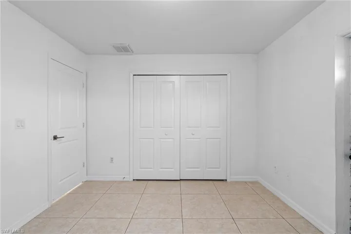 Unfurnished bedroom featuring light tile patterned flooring and a closet
