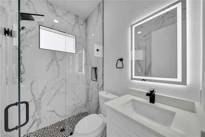 Bathroom featuring vanity and a marble finish shower