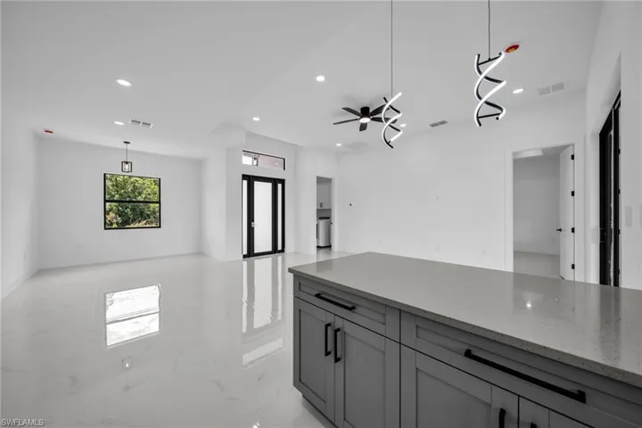 Kitchen with open floor plan, recessed lighting, light stone counters, gray cabinetry, and light marble finish flooring