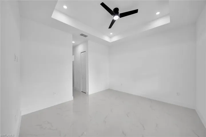 Unfurnished room featuring recessed lighting, a ceiling fan, marble finish flooring, and a raised ceiling