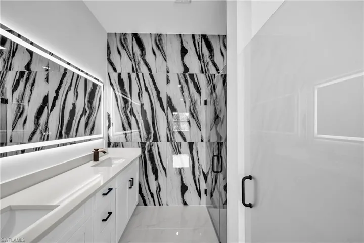 Bathroom featuring vanity and a marble finish shower