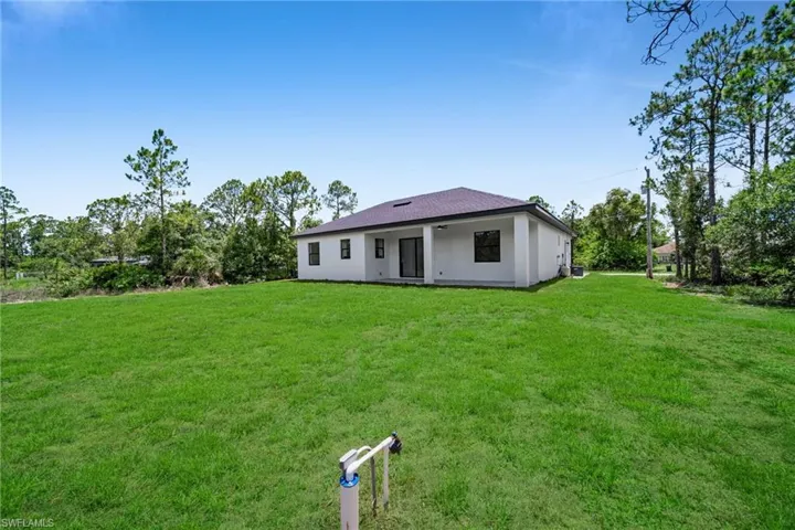 Rear view of house with a lawn and stucco siding