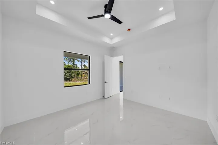 Spare room with a tray ceiling, recessed lighting, light marble finish flooring, and a ceiling fan
