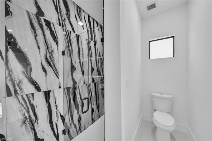 Bathroom with baseboards and a marble finish shower